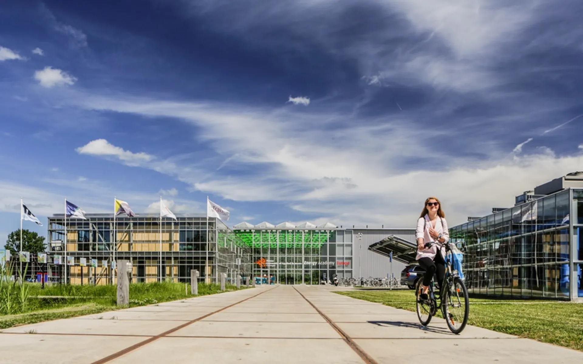 Vrouw fietst op een zonnige dag over het terrein van Entrance
