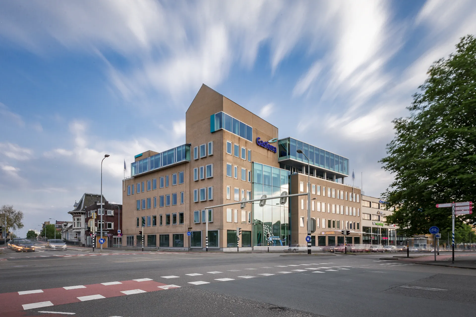 Kantoorgebouw GasTerra aan een kruispunt met bewolkte hemel.
