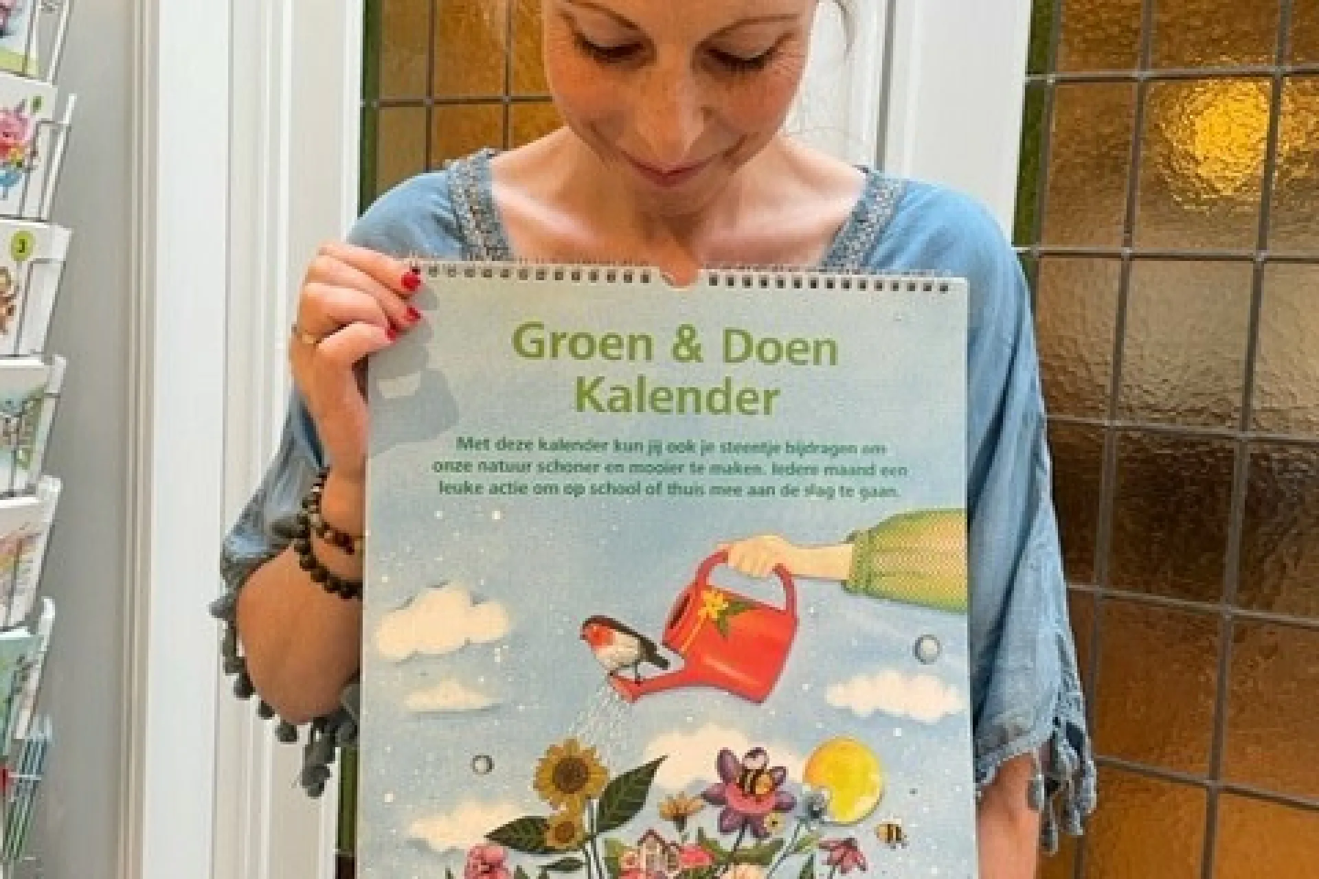 Een vrouw toont een kalender met kleurrijke illustraties van bloemen en vlinders.