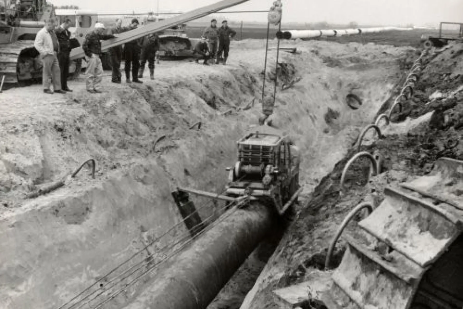 Mensen werken aan de installatie van een grote pijpleiding in een geul.